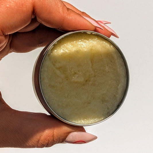 Holding an open pot of Creamy Oat Cleansing Balm.