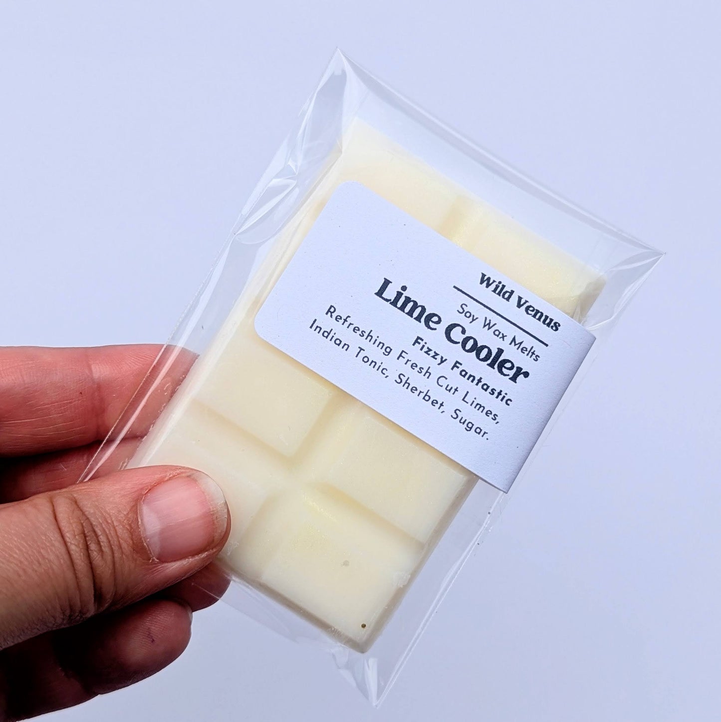 Holding a Lime Cooler soy wax melt against a white background.