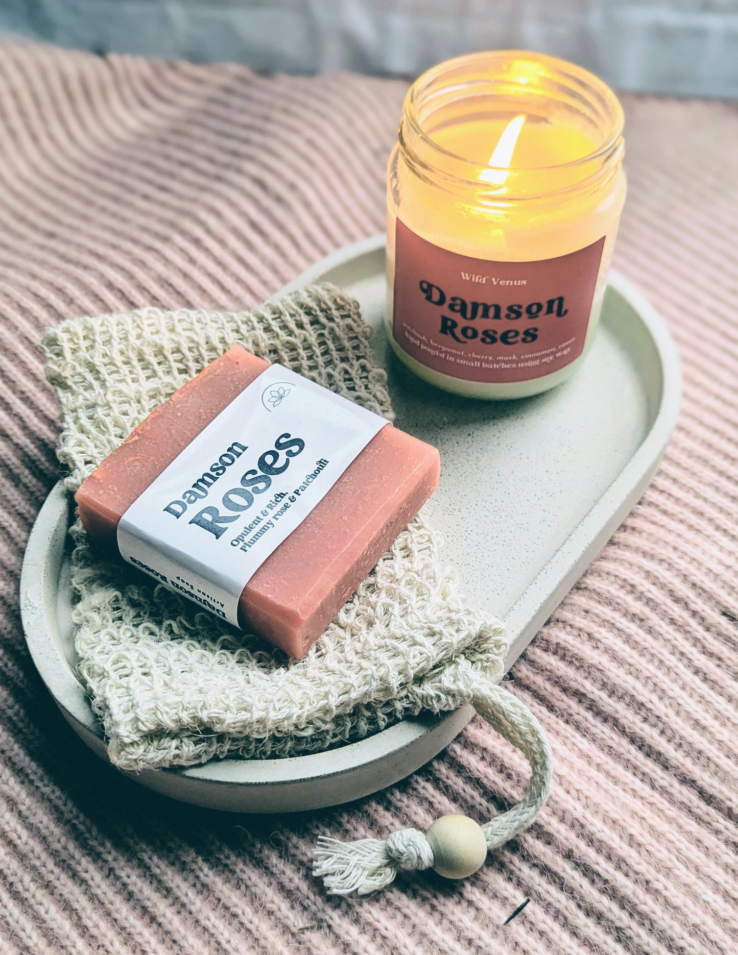 Damson roses soy candle and a rose soap on top of a soap saver pouch.