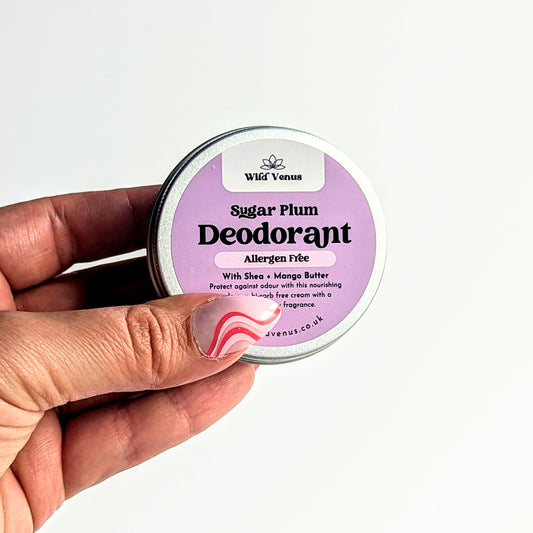 Holding a tin of Sugar Plum deodorant against a white background.