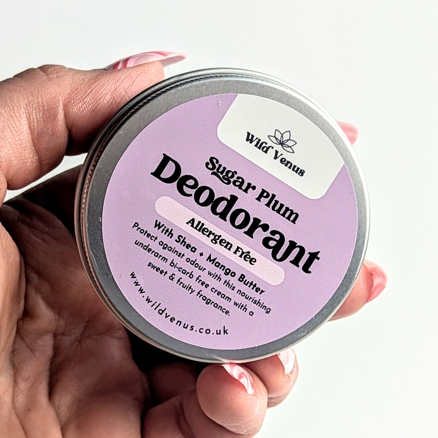 A close up of holding a tin of Sugar Plum sensitive deodorant.