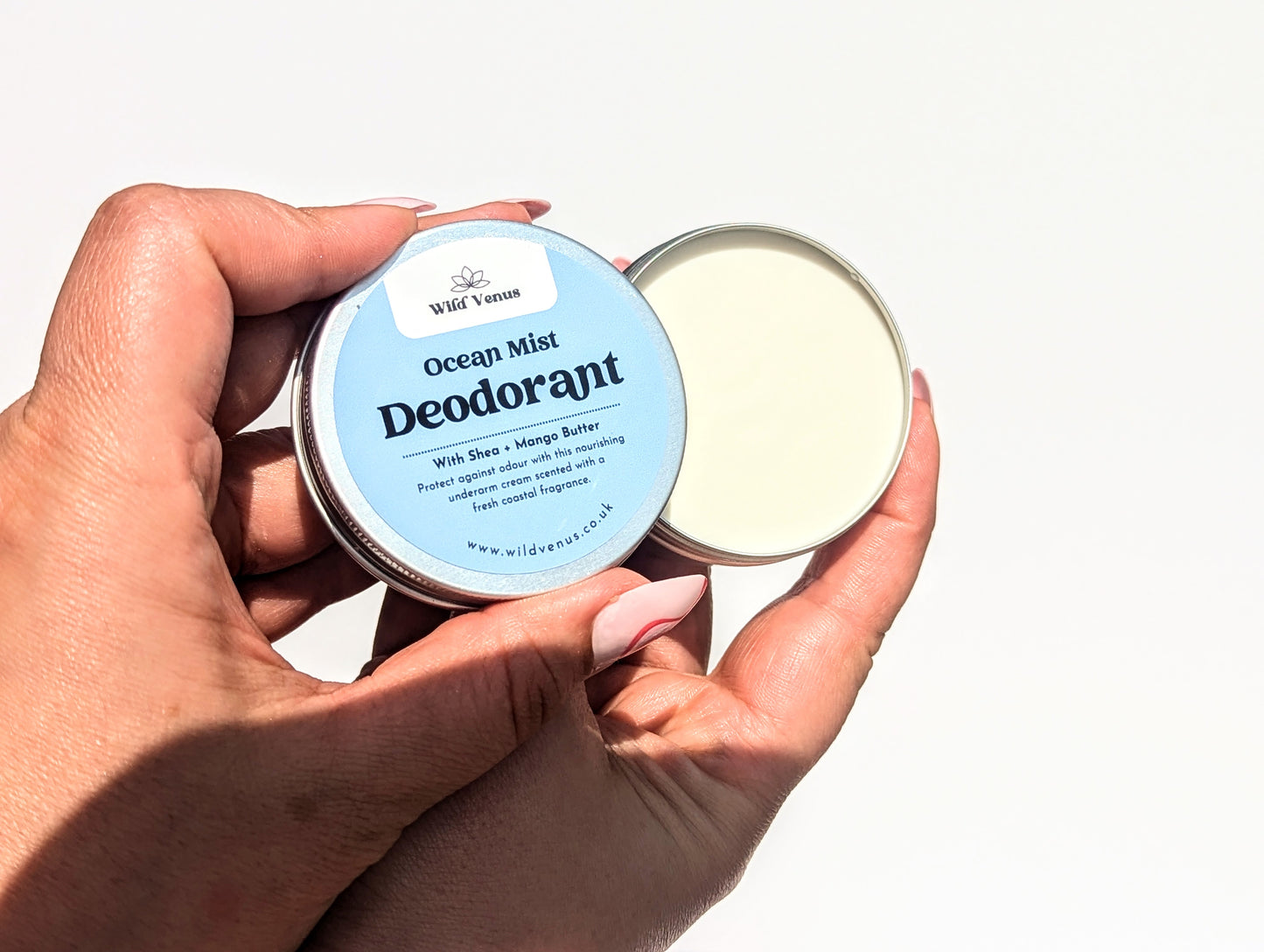 Opening a pot of the Ocean Mist deodorant against a white background. There is a shadown being cast on the lower part of the hands.
