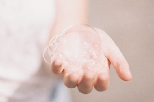 A photo of a woman's hand holding a big frothy bubble. Photo taken by Matthew Tkocz
