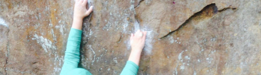 A close up of chalky hands on rock.