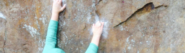 A close up of chalky hands on rock.