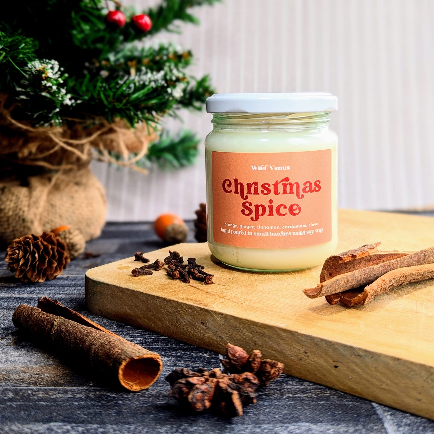 A lit soy candle in the fresh linen scent is positioned on a light pink jumper.