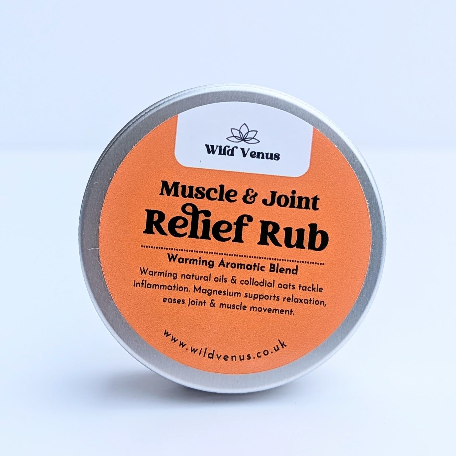 A tinof muscle relief rub is in the foreground and on a white surface, a tattoo balm is behind and out of focus.