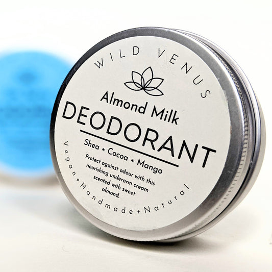 A tin of Almond Milk Deodorant in the foreground and a blurry tin of Sea Spray Deodorant in the background.