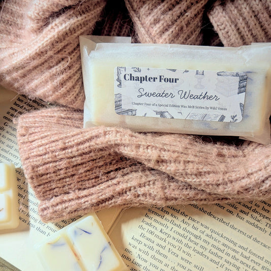 Wax melt with a label and knitted sweater, placed on an open book.