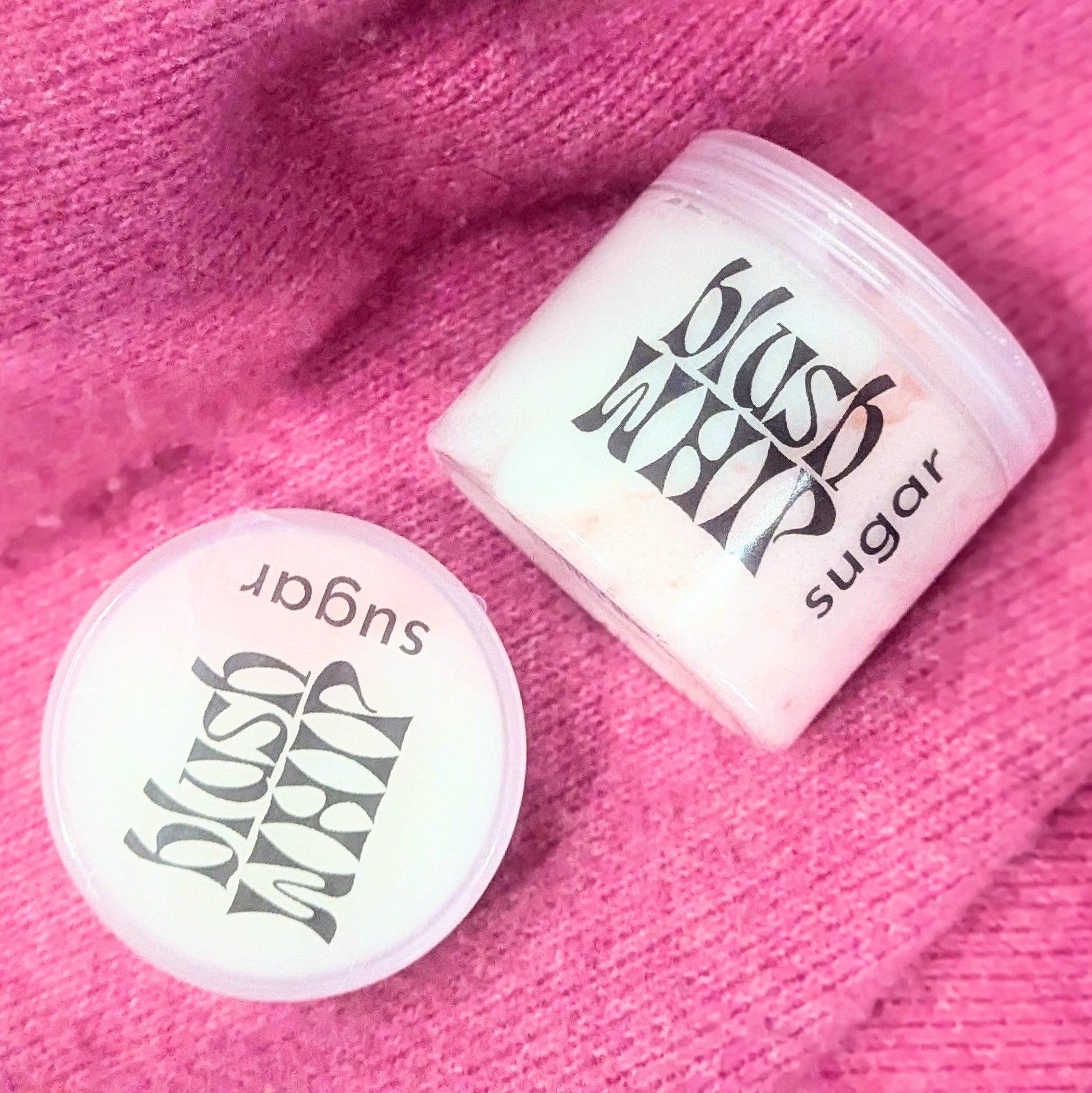 Blush whip sugar scrub on a pink textile background.