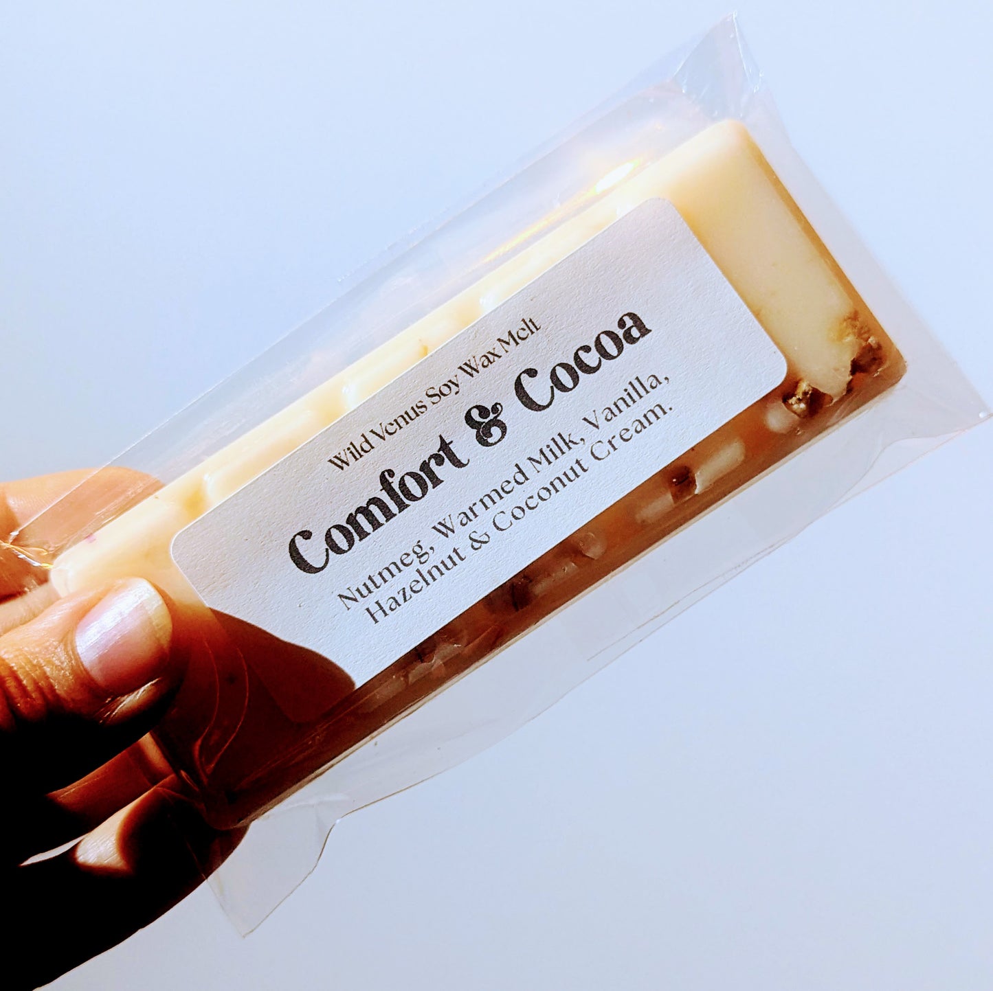 Holding the comfort and cocoa soy wax melt against a white background.