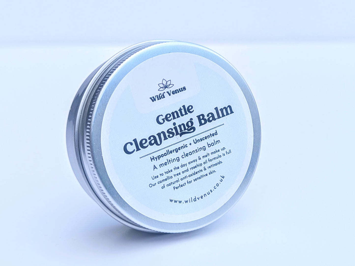 A tin of Gentle Cleansing Balm on its side and tilted slightly away from the camera with the front of the label showing. The product is against a plain white background. 