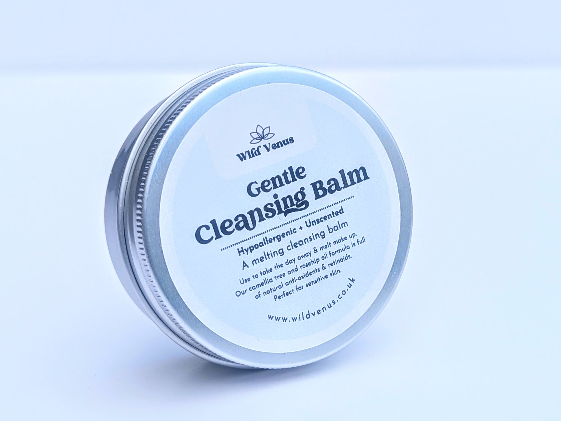A tin of Gentle Cleansing Balm on its side and tilted slightly away from the camera with the front of the label showing. The product is against a plain white background. 
