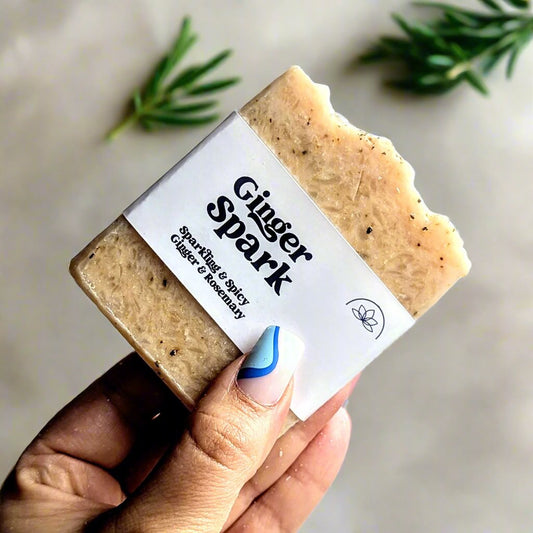 Holding a bar of Ginger spark vegan soap infant of sprigs of rosemary.
