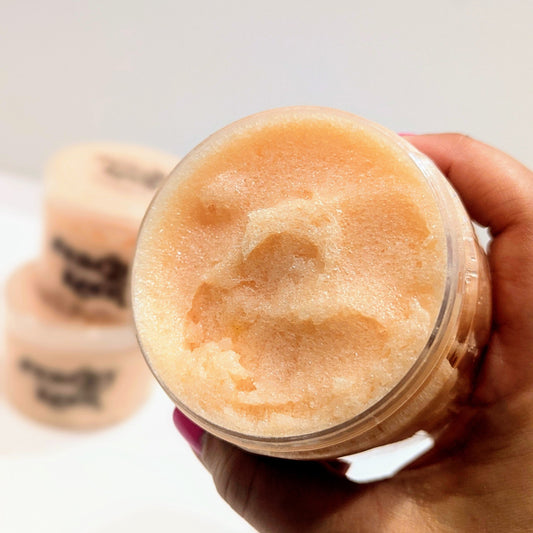 Hand holding a container of peach coloured product with a blurred background
