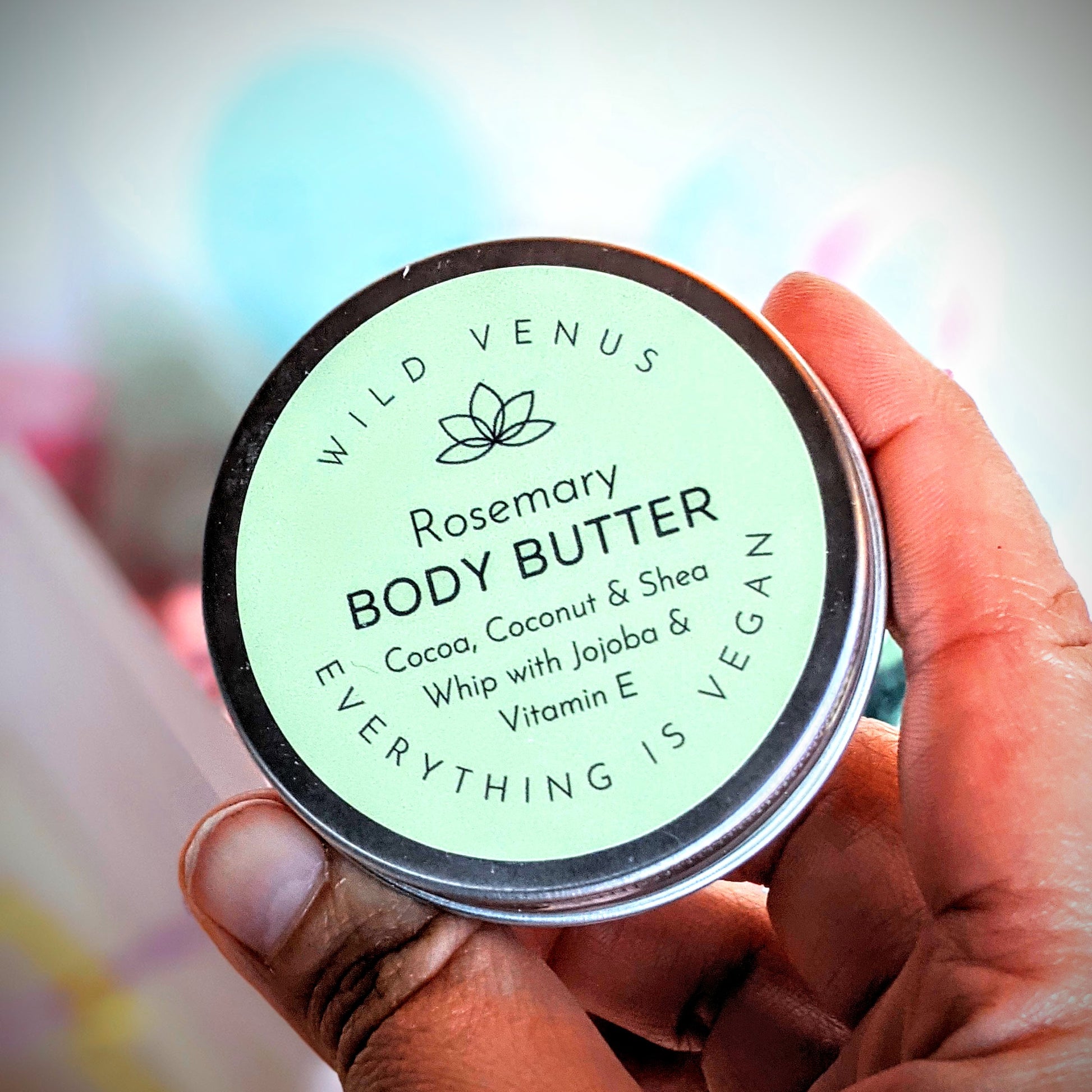 Naomi is holding a tin of the rosemary body butter. 