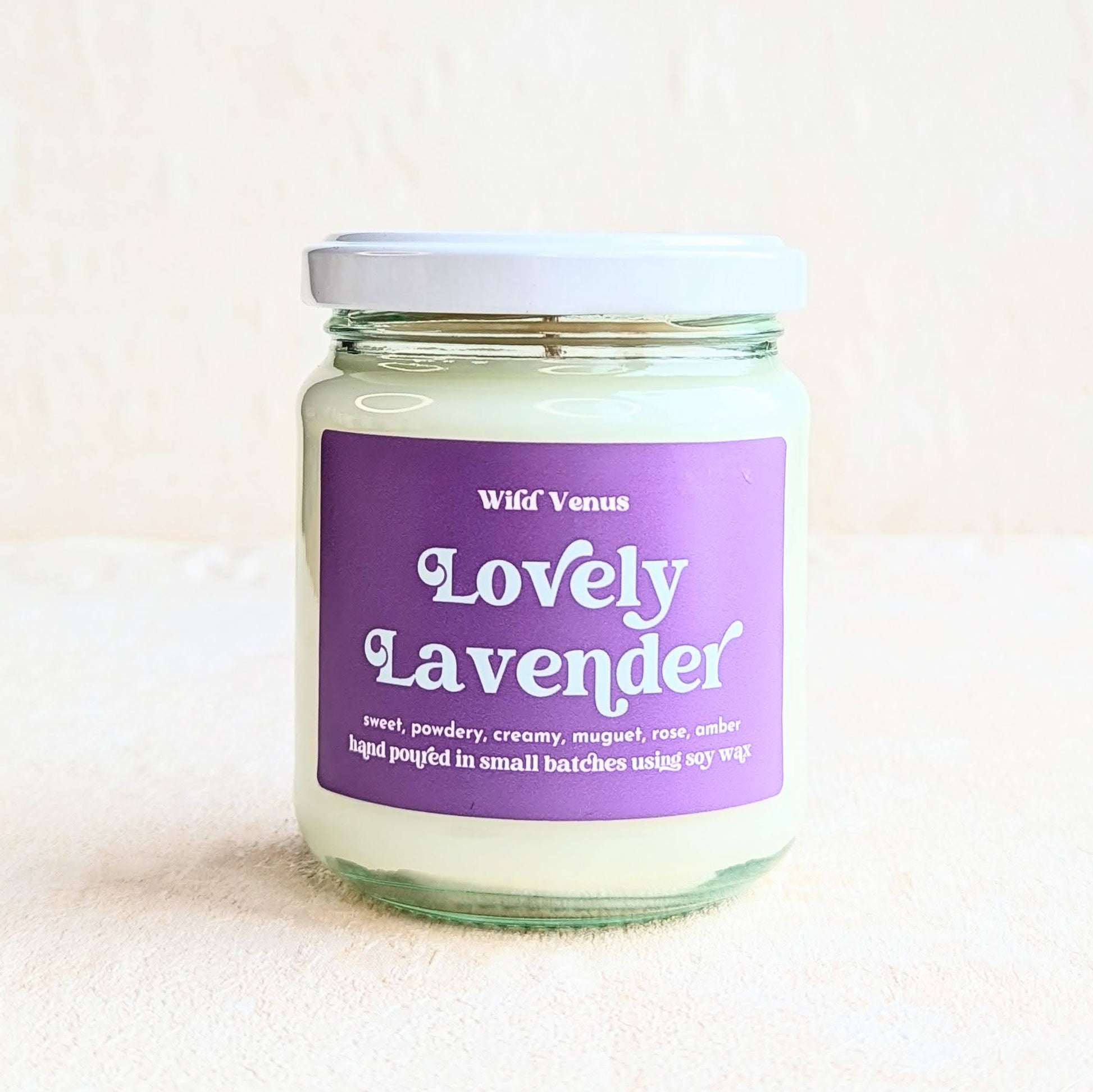 A square photo featuring the Lovely Lavender container candle on a plain white surface and background. 