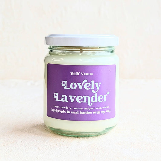 A square photo featuring the Lovely Lavender container candle on a plain white surface and background. 