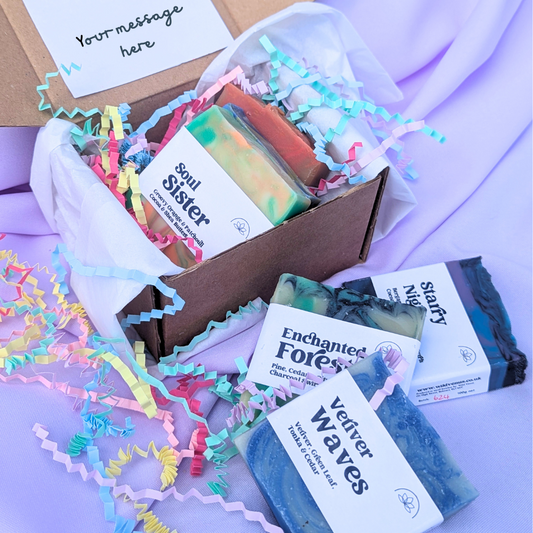 Photo shows 5 soap bars in and around an open box. 