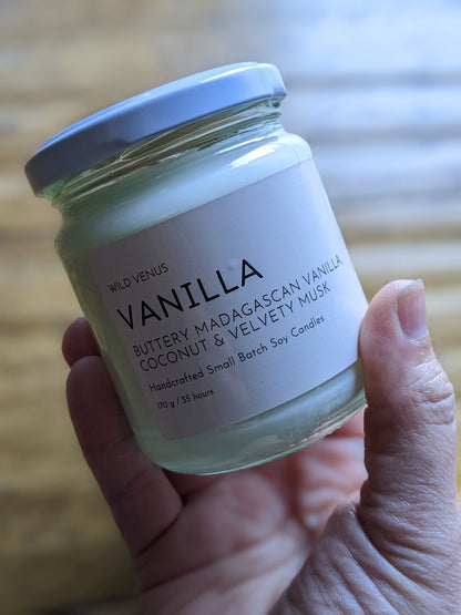Holding a vanilla scented candle with Wild Venus branding.