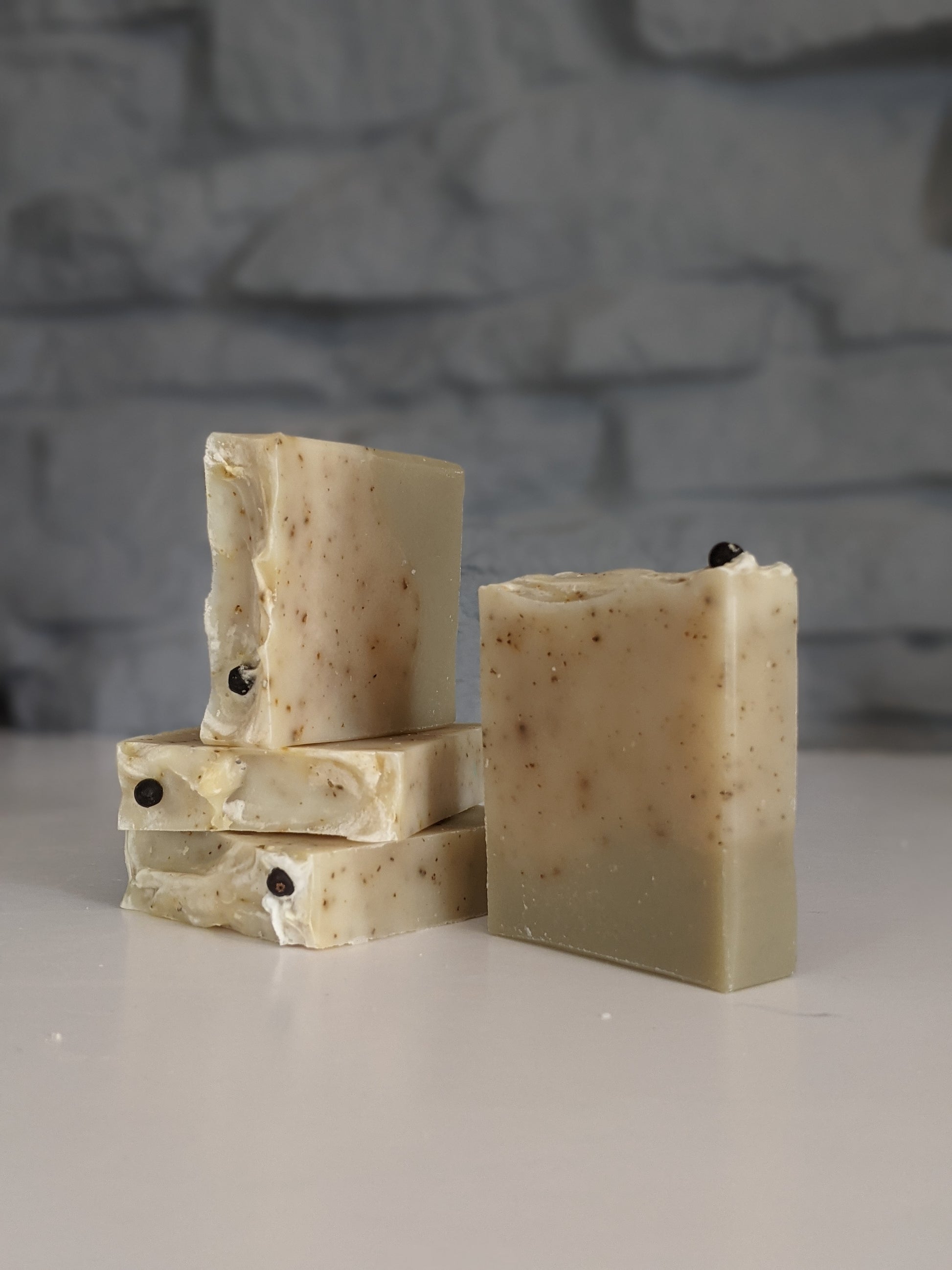 4 herb garden soaps arranged on a white surface against a light grey brick background. 