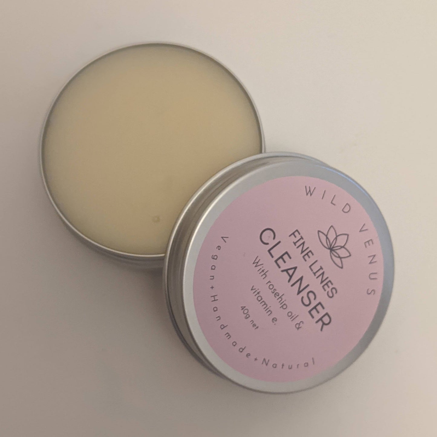 A open pot of the Wild Venus Fine Lines Cleansing Balm on a white background.