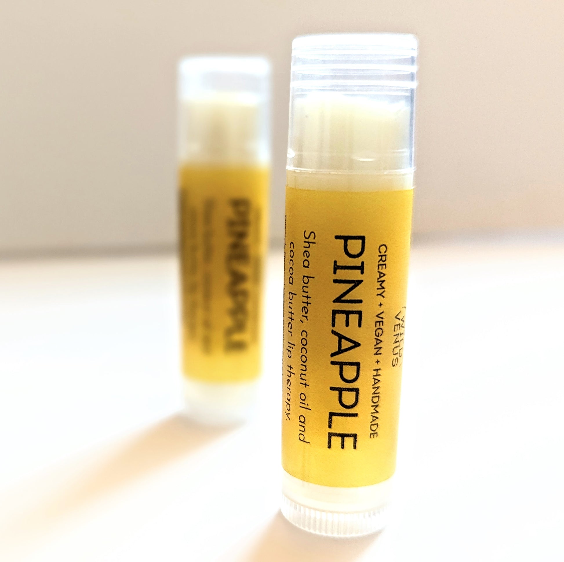 Two tubes of Pineapple Lip Balm with one in focus. 