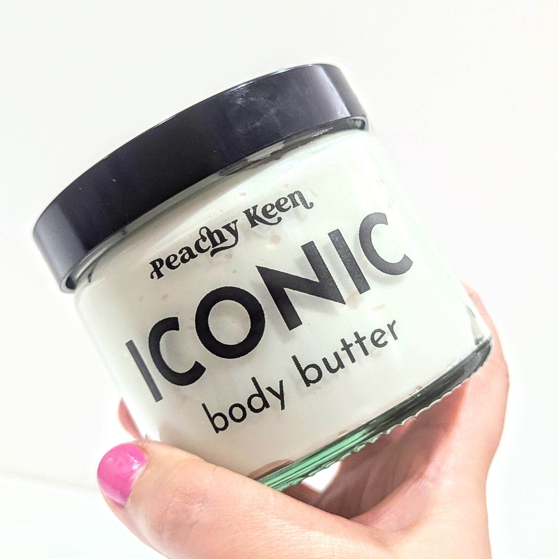 Hand holds the Peachy keen iconic body butter.