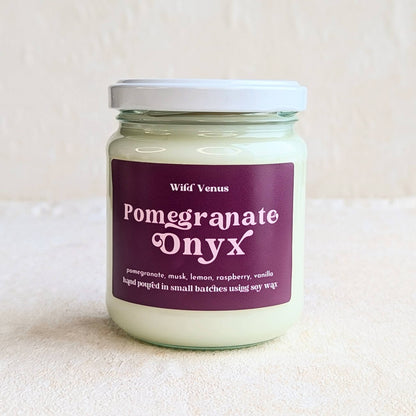 The pomegranate onyx soy candle with a lid against white background.