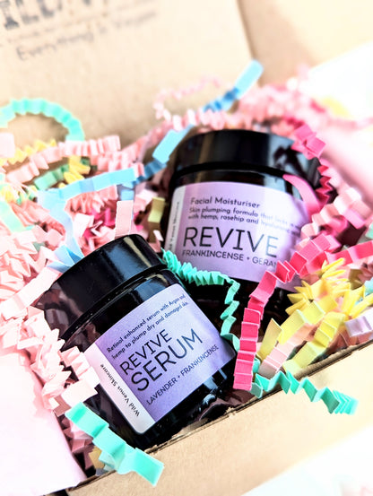 Revive Serum and Moisturiser shown in a gift box with pastel coloured shredded paper. 
