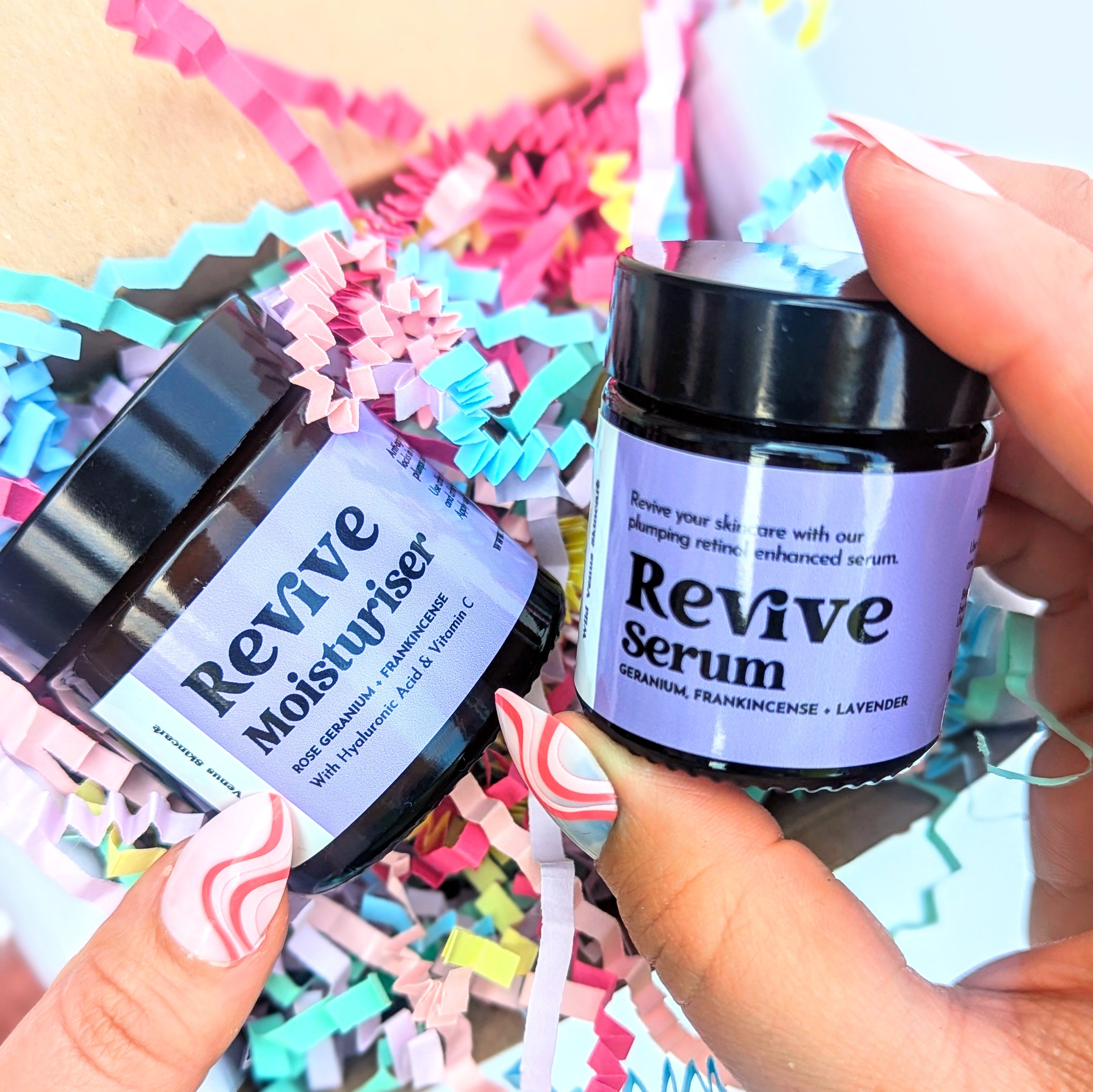 Holding a Revive SKincare Duo Gift Box. The right hand holds up the Revive Serum. 