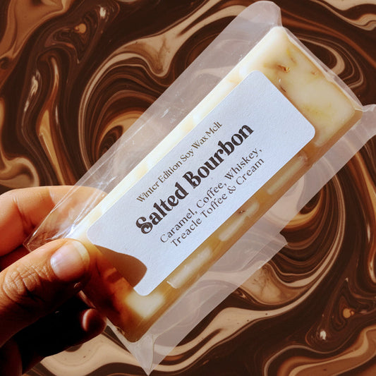 A hand holds the salted bourbon soy wax melt against a swirled brown and cream background.