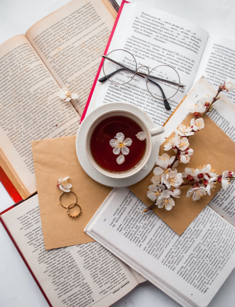 Blossom tea wax melt image of a cup of tea on open books, there's a pair of reading glasses and flowers on top also.