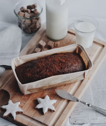 A gingerbread loaf and some iced gingerbread stars on a chopping board. 