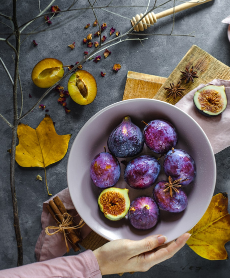 A bowl of figs with plums, star anise and cinnamon with autumnal styling. 
