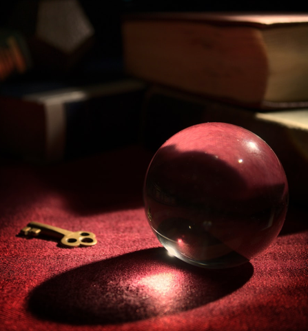 A fortune teller ball with a key and old books. 