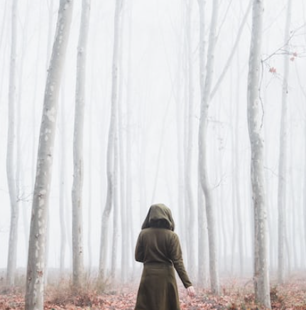 A woman standing in a forest of white birch trees.