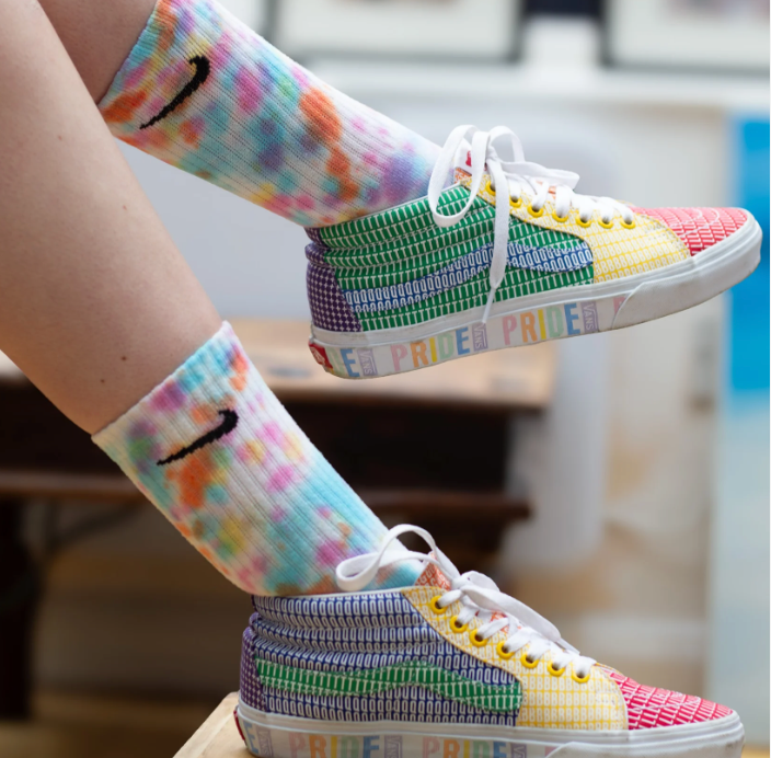 A model wears Snow Moon Creations colourful Nike socks in the Rainbow melt. 