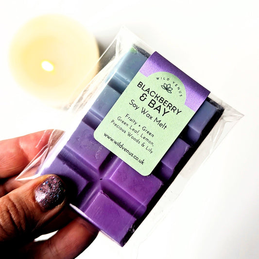 holding a Soy wax melt in the Jo Malone Blackberry and Bay scent. A candle is in the background. 