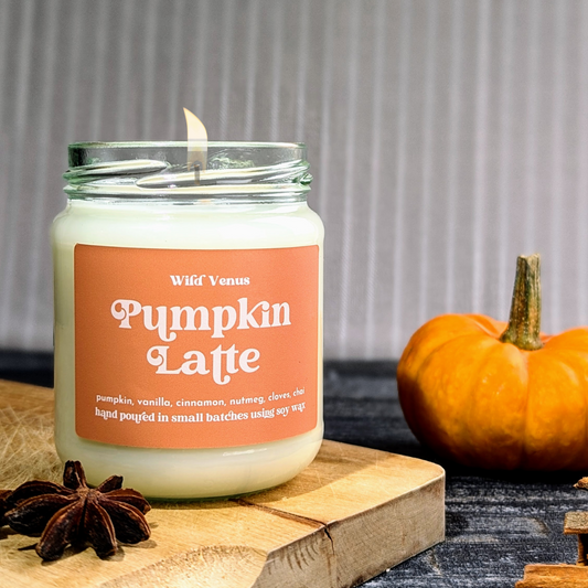 The Pumpkin candle is on a wooden chopping board. There is a mini pumpkin in the background.