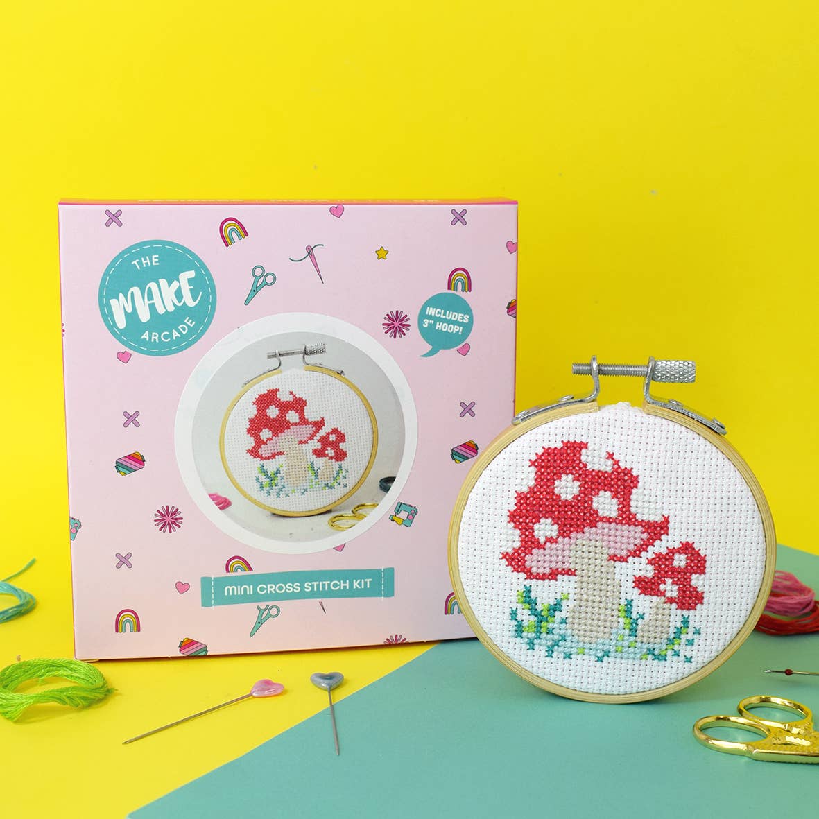 A completed 'Toadstool' mini cross stitch kit next to the presentation box.