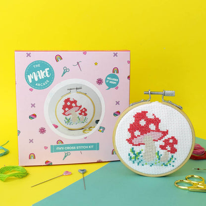 A completed 'Toadstool' mini cross stitch kit next to the presentation box.