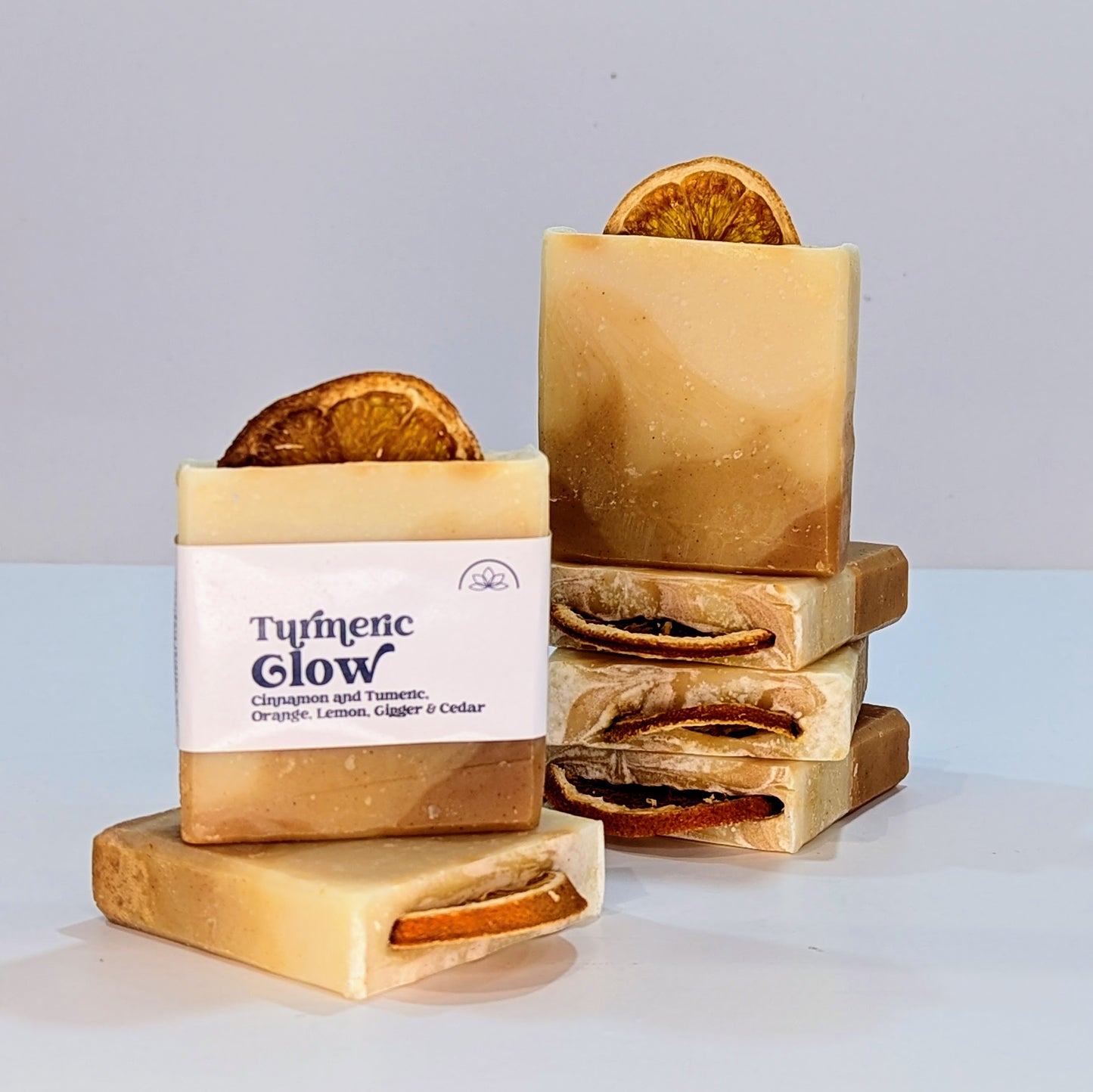 Two stacks of bright orange layered handmade soaps. One soap has a label which says Turmeric Glow.