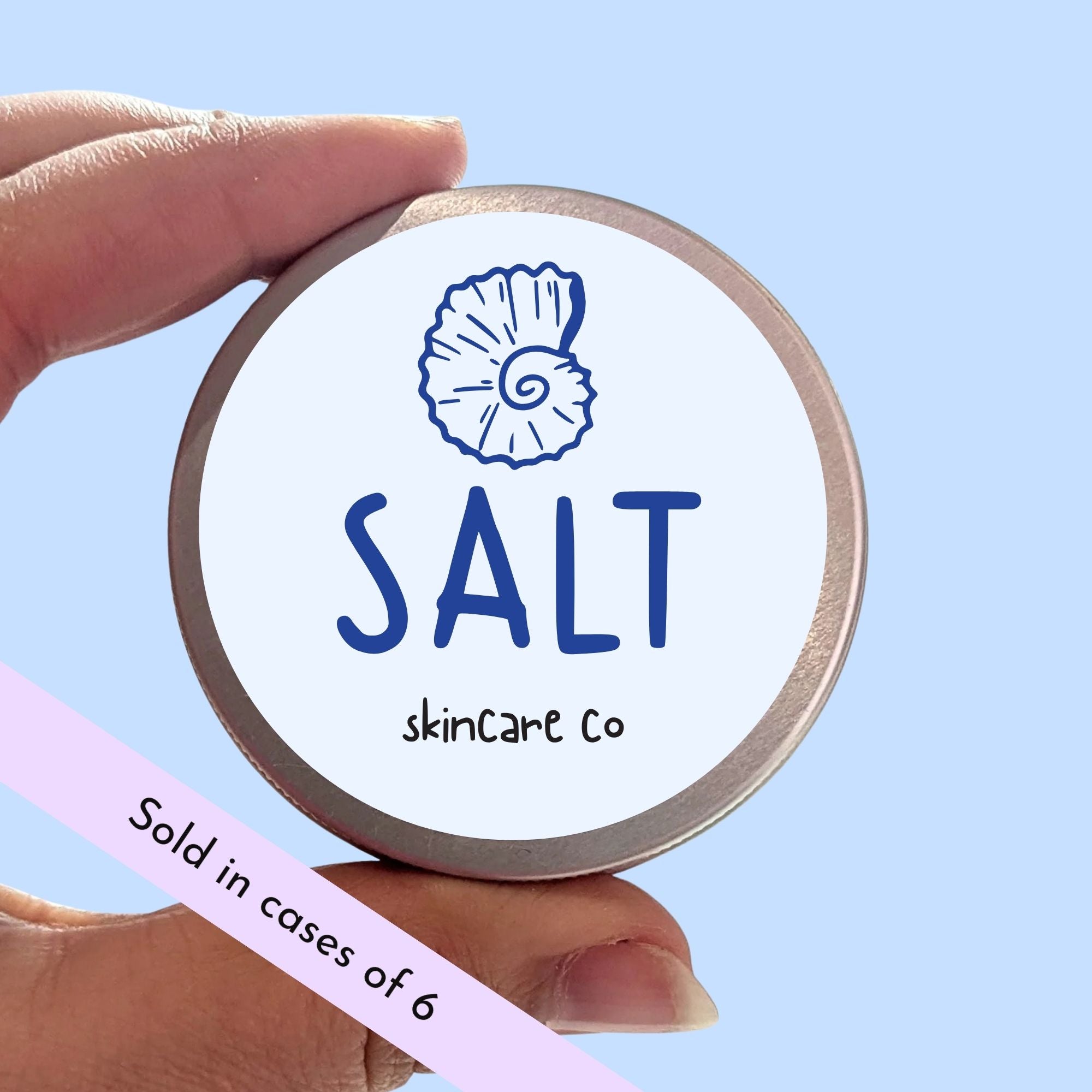 Hand holding a container with 'SALT skincare co' branding against a light blue background