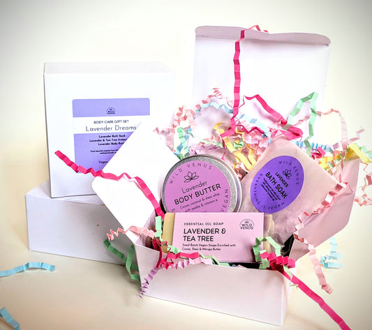 An open box of the lavender dreams body beautiful gift set, infront of two more stacked gift boxes.