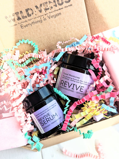 A gift box of Revive Serum and Moisturiser with  pastel coloured shredded paper. 