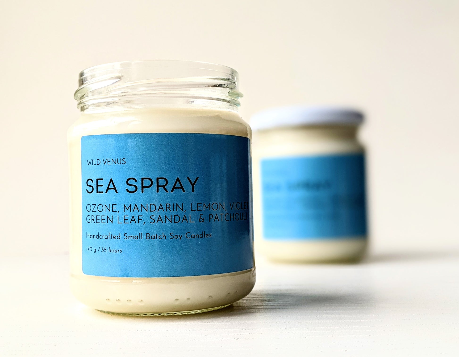 An open Sea Spray scented candle in front of a closed Sea Spray soy candle