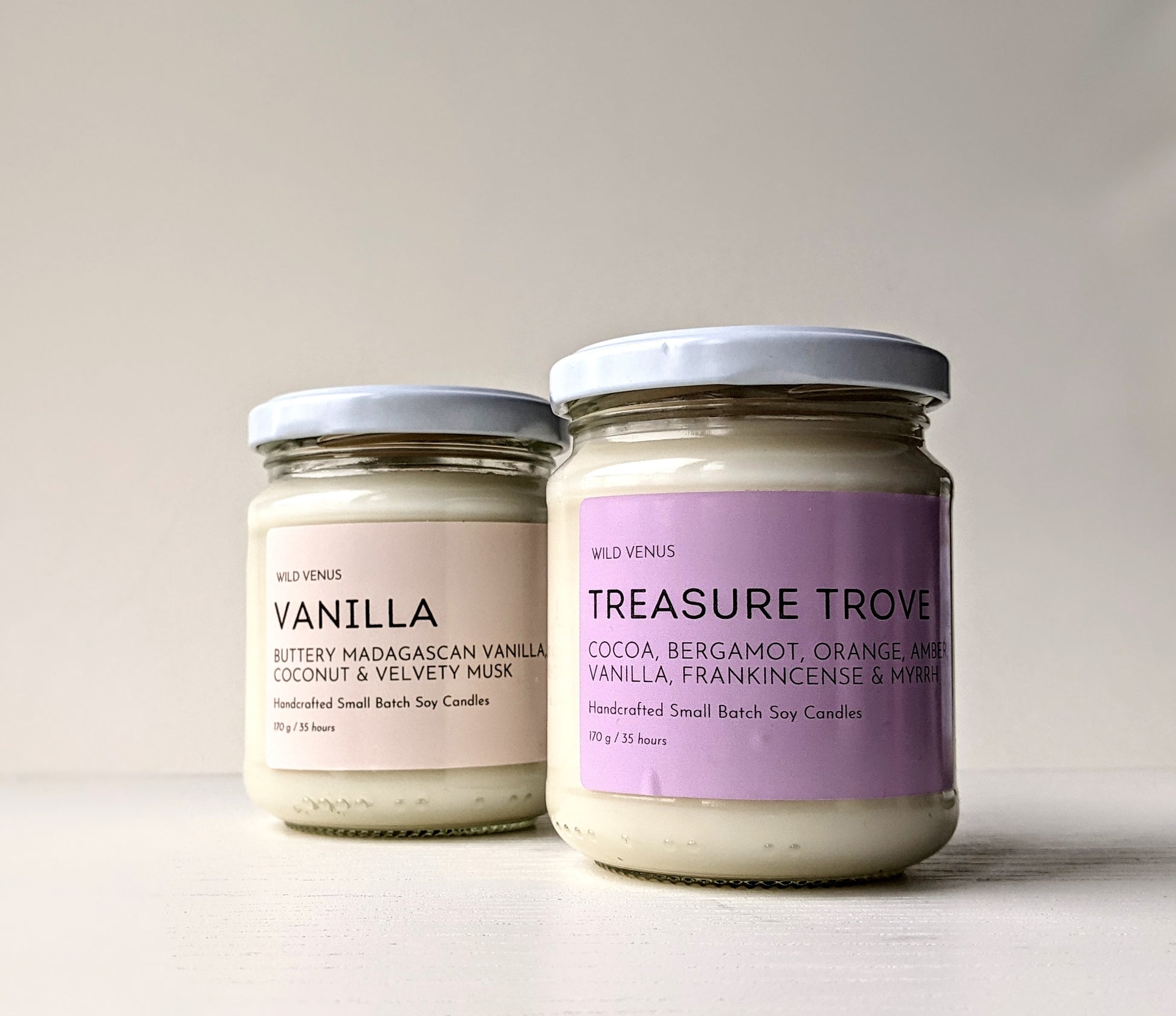 A vanilla candle is behind a treasure trove candle.