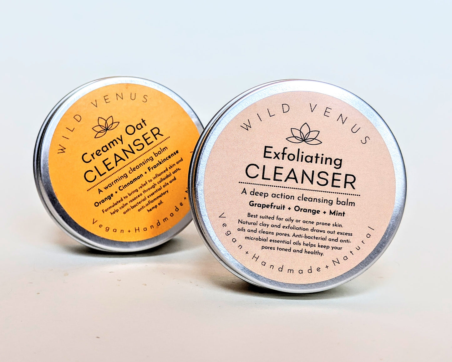 An exfoliating cleanser balm in front of a creamy oat cleanser balm. 