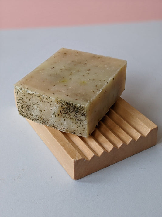 Wooden soap dish with a natural soap on top. 